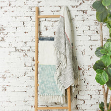 luna throw blankets styled on ladder shelf propped against a white brick wall