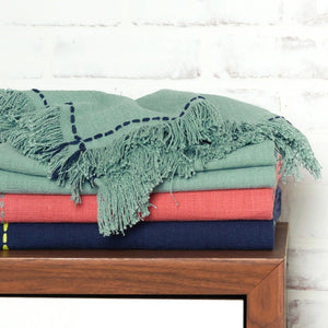 cheryl mint teal pink and indigo throw blankets folded and stacked on a table