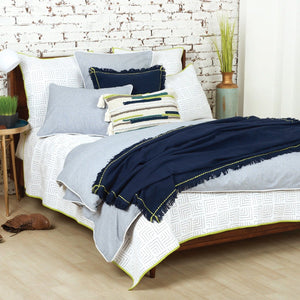 indigo cheryl throw blanket with green blanket stitch and fringed edge styled on gray and white bedding