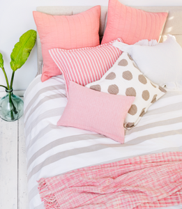 tan and white polka dot decorative pillow with hand-stitched edge styled on pink bedding