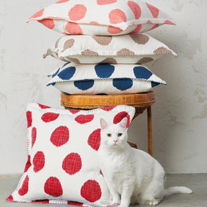 cat standing in front of polka dot decorative pillows stacked on a stool