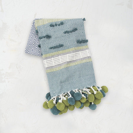 green blue and white patterned highland throw blanket with pom pom tassel fringe