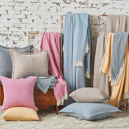 langford throw blankets and pillows displayed against a white brick wall