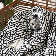 cat snuggling in naya black and white geometric pet quilt