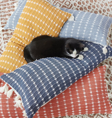 cat resting on the riley decorative throw pillows featuring a raised stitch texture and tasseled fringe